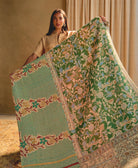 woman holding a green floral kantha quilt against a beige background