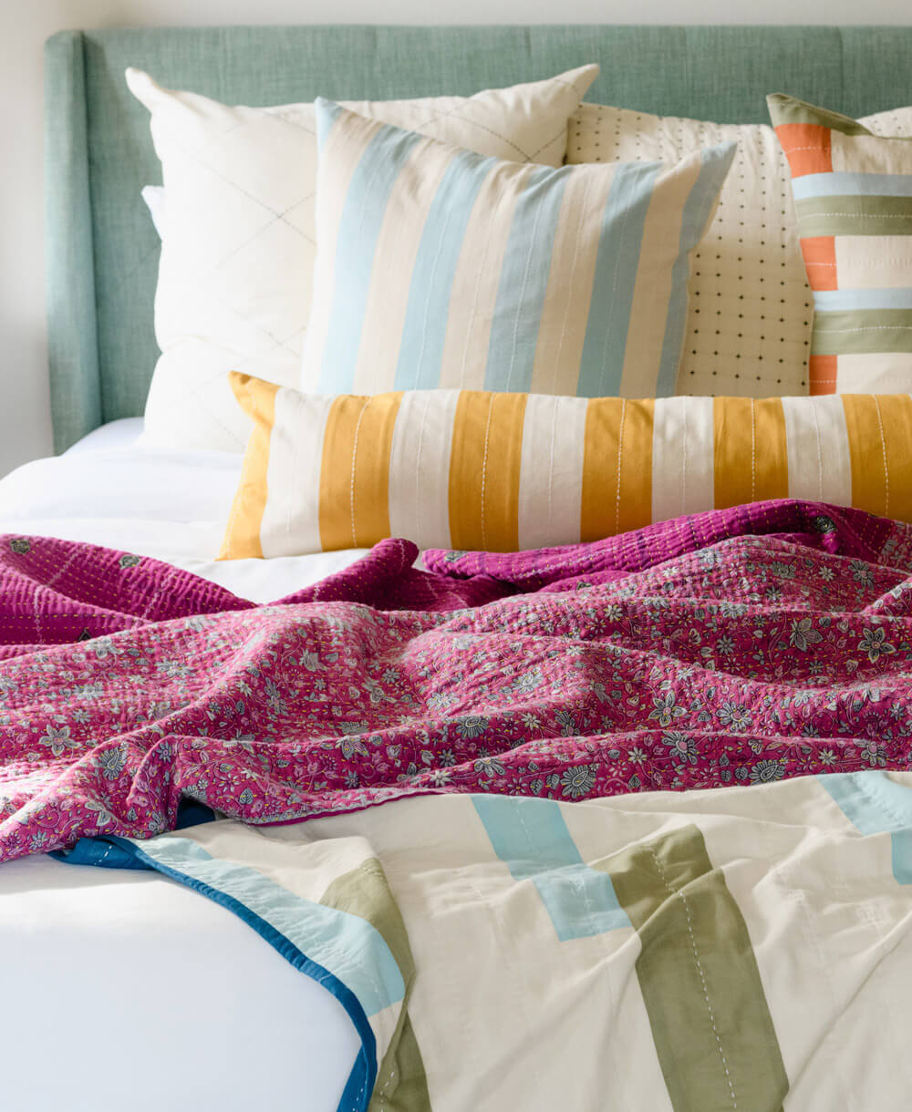 hot pink kantha blanket draped over organic cotton colorblock bedding with coordinating pillows