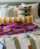 handmade magenta kantha quilt throw draped over colorful queen bed in modern bedroom