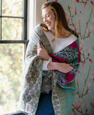 kantha quilt draped around woman's shoulders in shades of magenta and blue