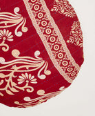 red circle pillow with tan traditional print with blue hand-stitching made by women artisans