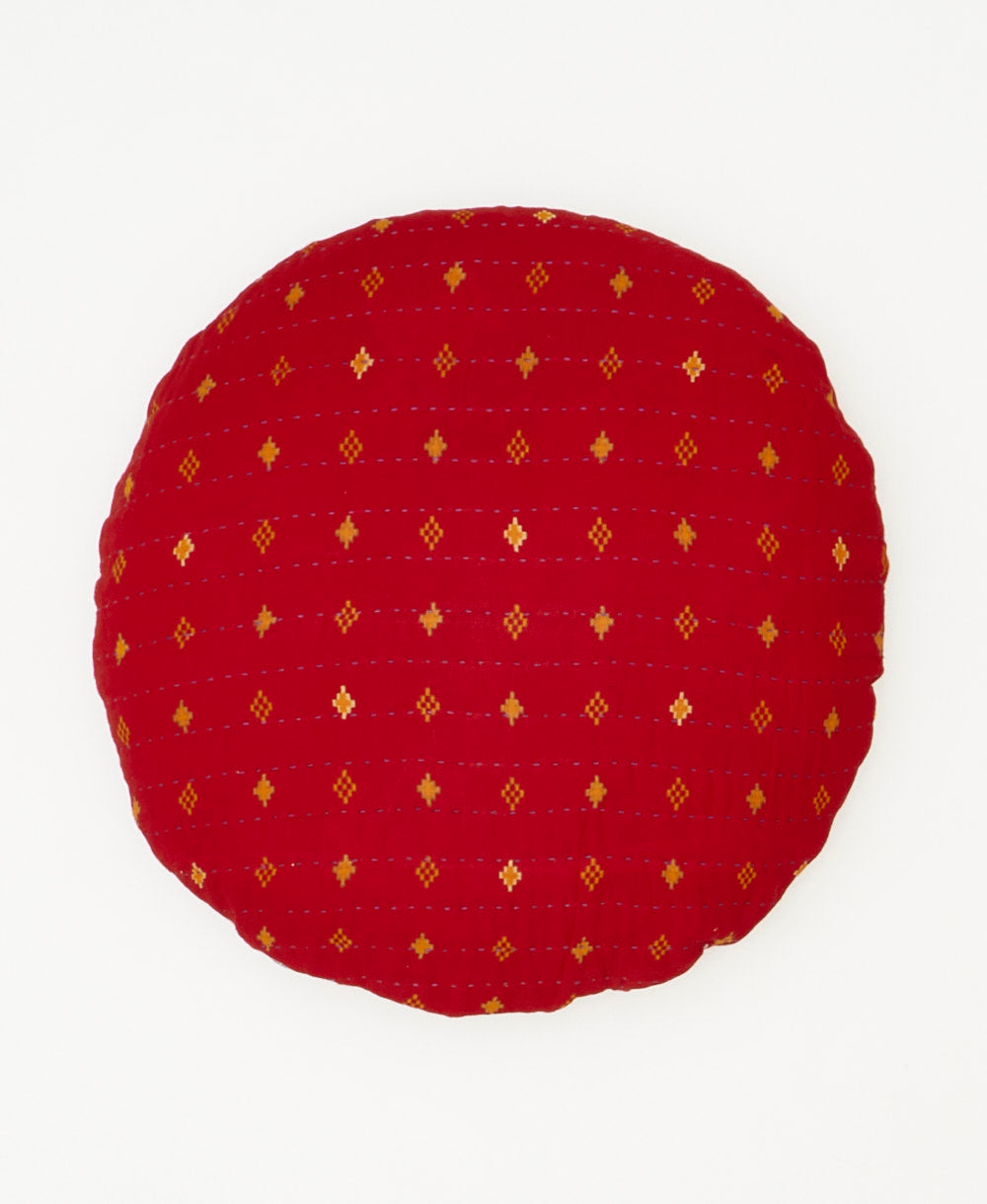 made by artisans in india, this round throw pillow features an orange diamond print 