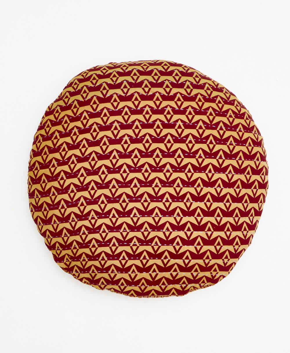 tan and red round pillow with a diamond pattern