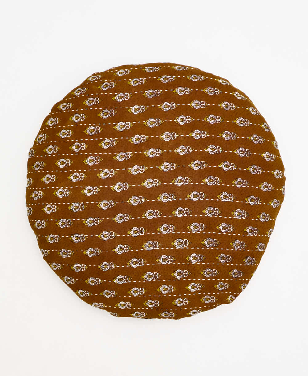 caramel brown round pillow with white and yelow paisley details 