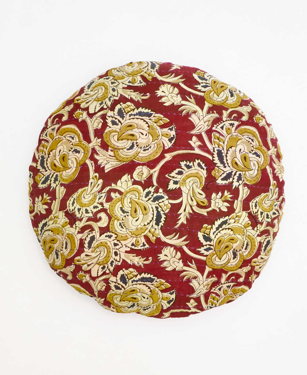 red and yellow round pillow with an oversized floral print 