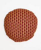 dark red and yellow round pillow with a repeating diamond pattern