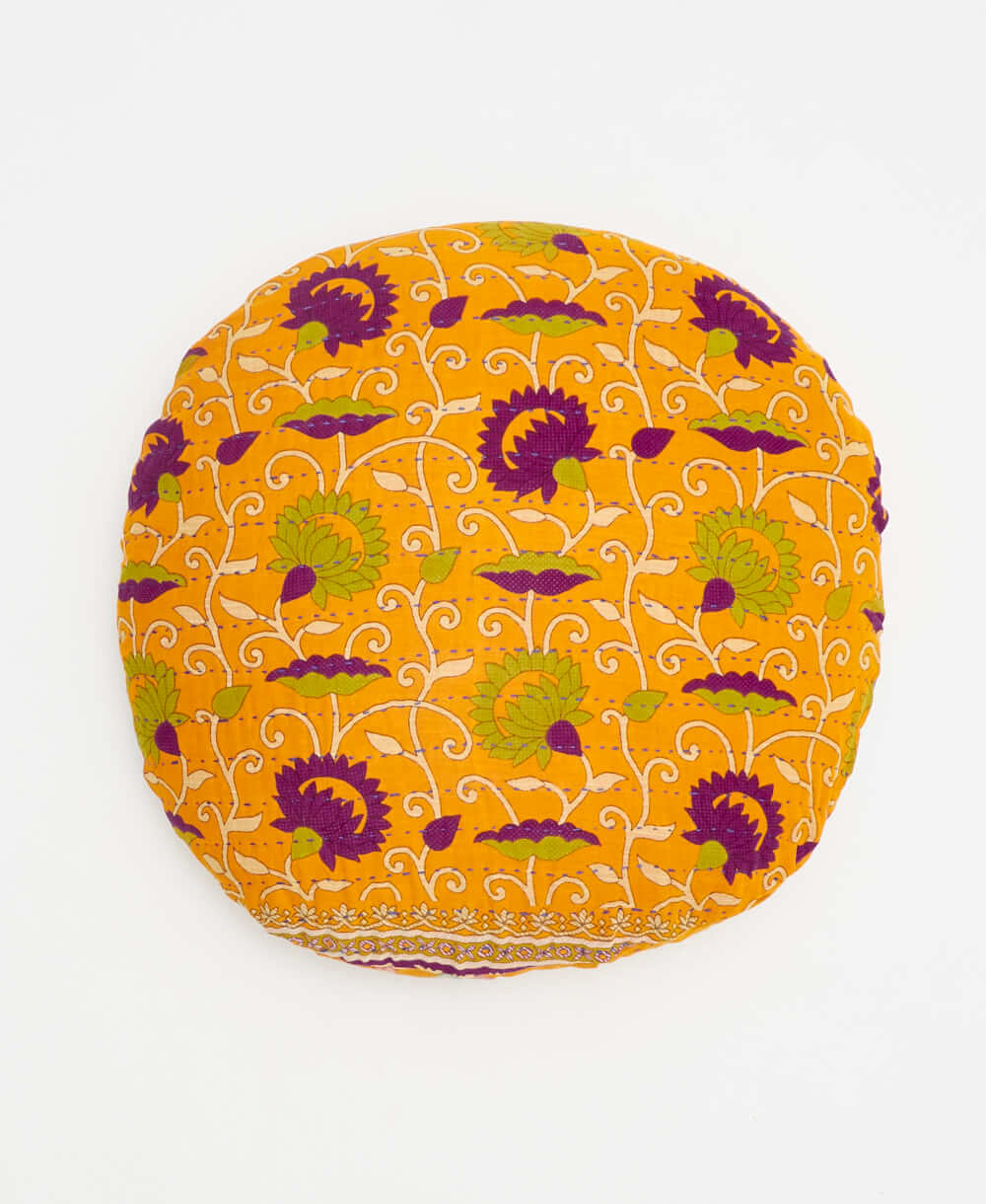 orange round pillow with green and purple swirling floral details 