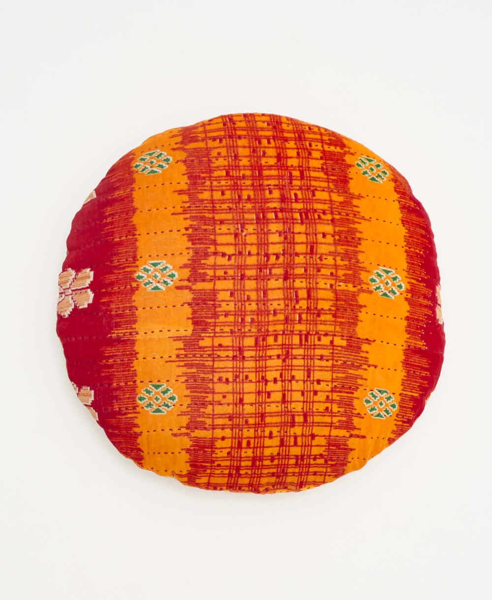 orange and red round pillow with green geometric details 