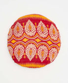 red round pillow with white and orange paisley details 