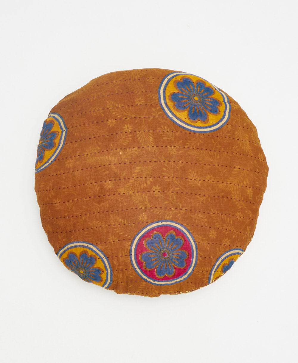 brown, yellow, and blue round pillow with handstitched details 