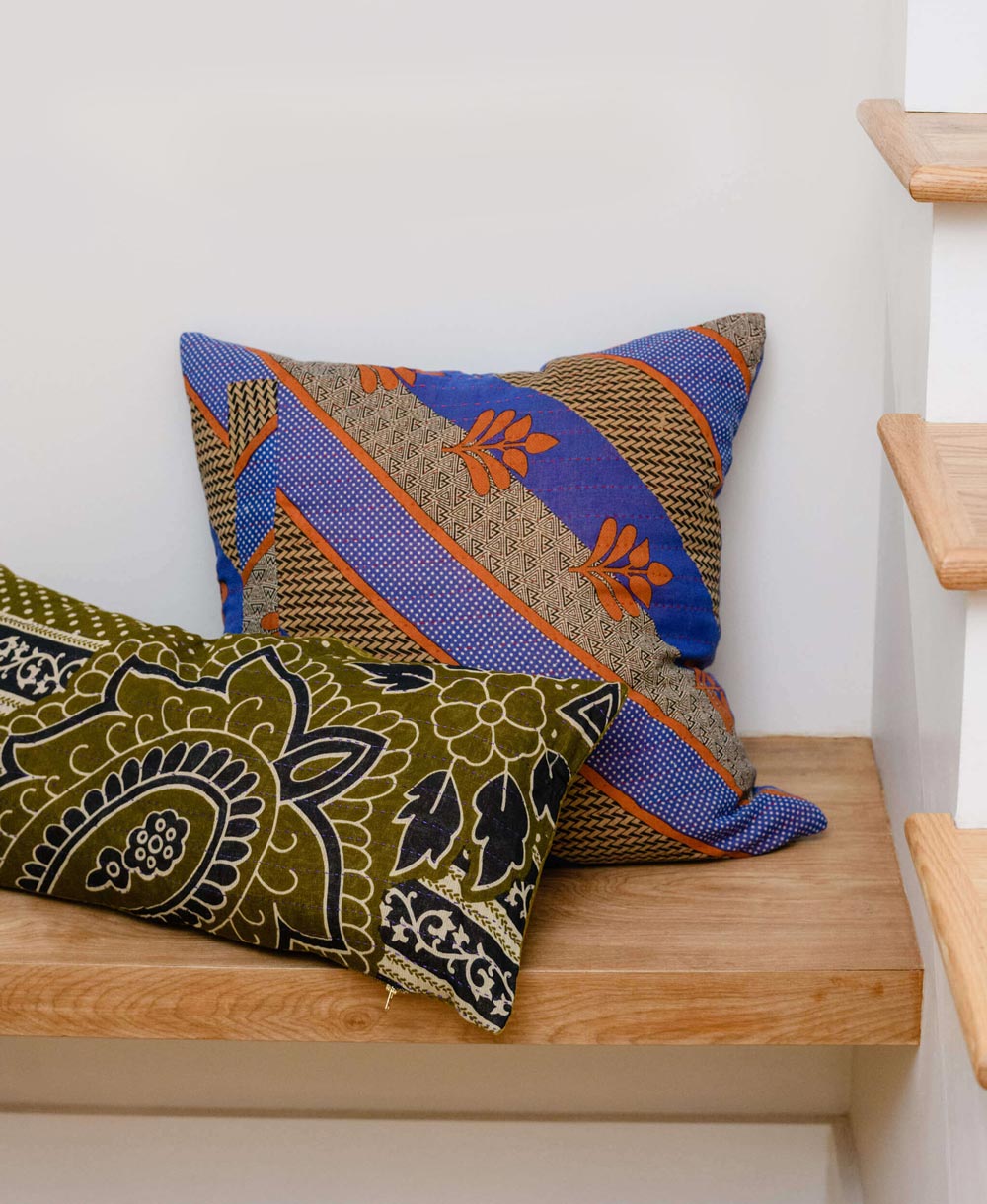 blue and orange throw pillow and green lumbar pillow sitting on wooden entryway bench