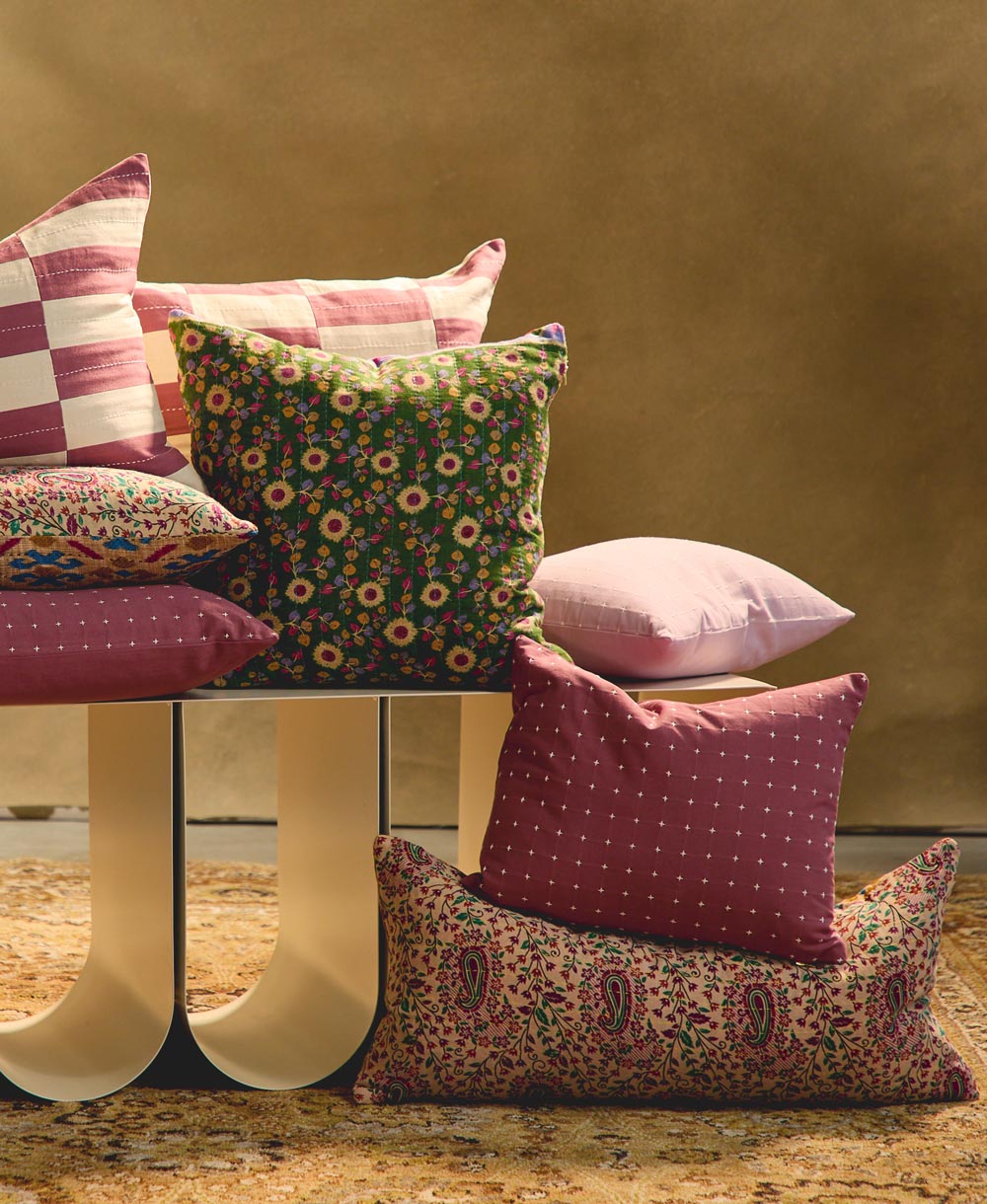 purple and green floral and paisley throw pillows sitting on white modern bench with traditional rug