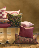 purple and green floral and paisley throw pillows sitting on white modern bench with traditional rug