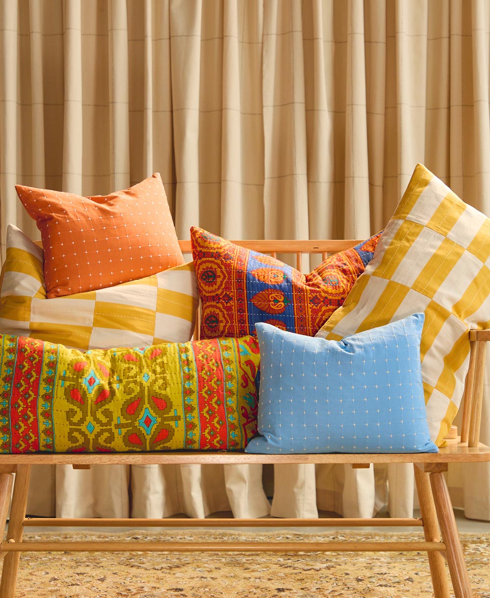 colorful organic cotton and vintage throw pillows on light wooden modern bench