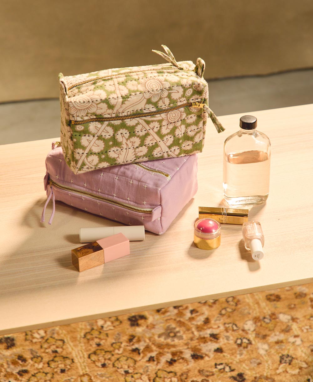 Two makeup bags on a surface with small makeup items around
