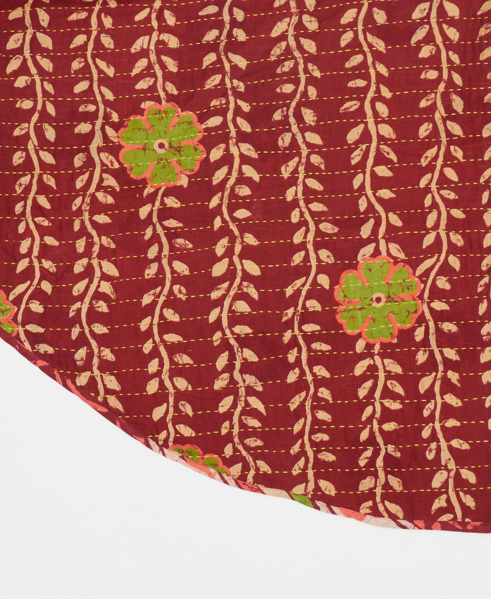 brick red reversible tree skirt made with a tan vine pattern and yellow kantha stitching