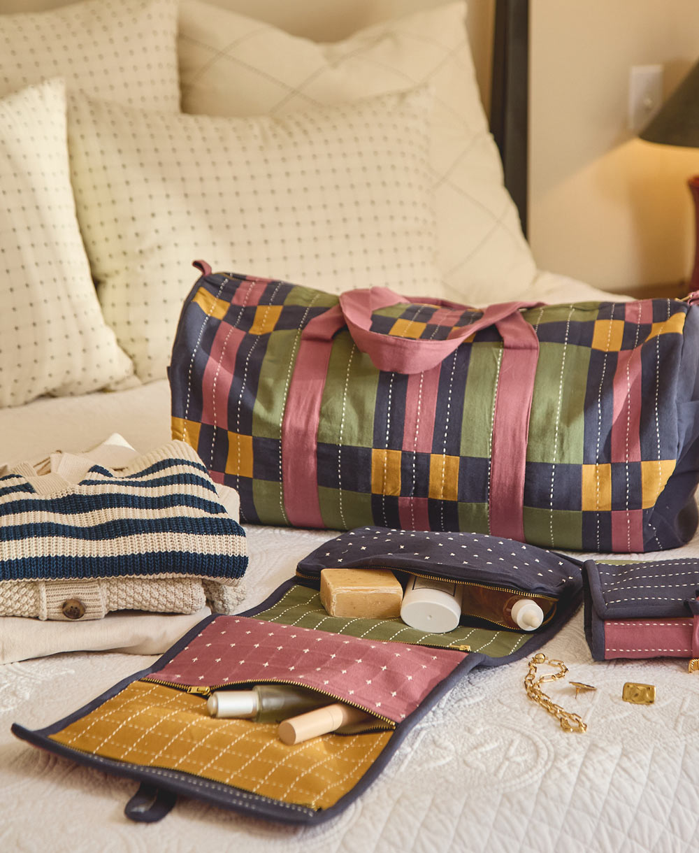 large toiletry bag on white bedspread with other matching travel accessories
