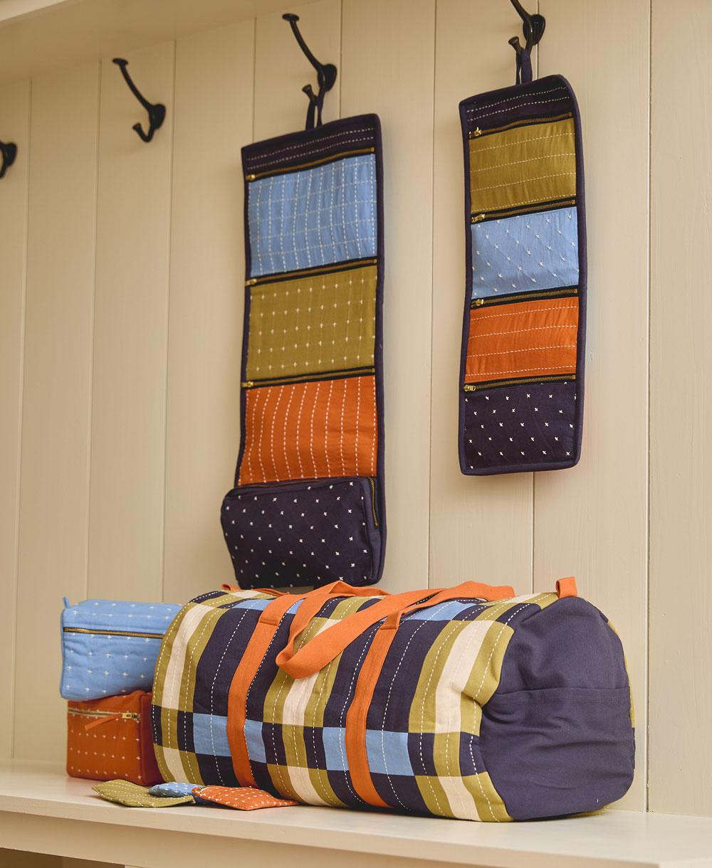 colorful travel organizers hanging on wall with black hooks and matching colorful duffle bag