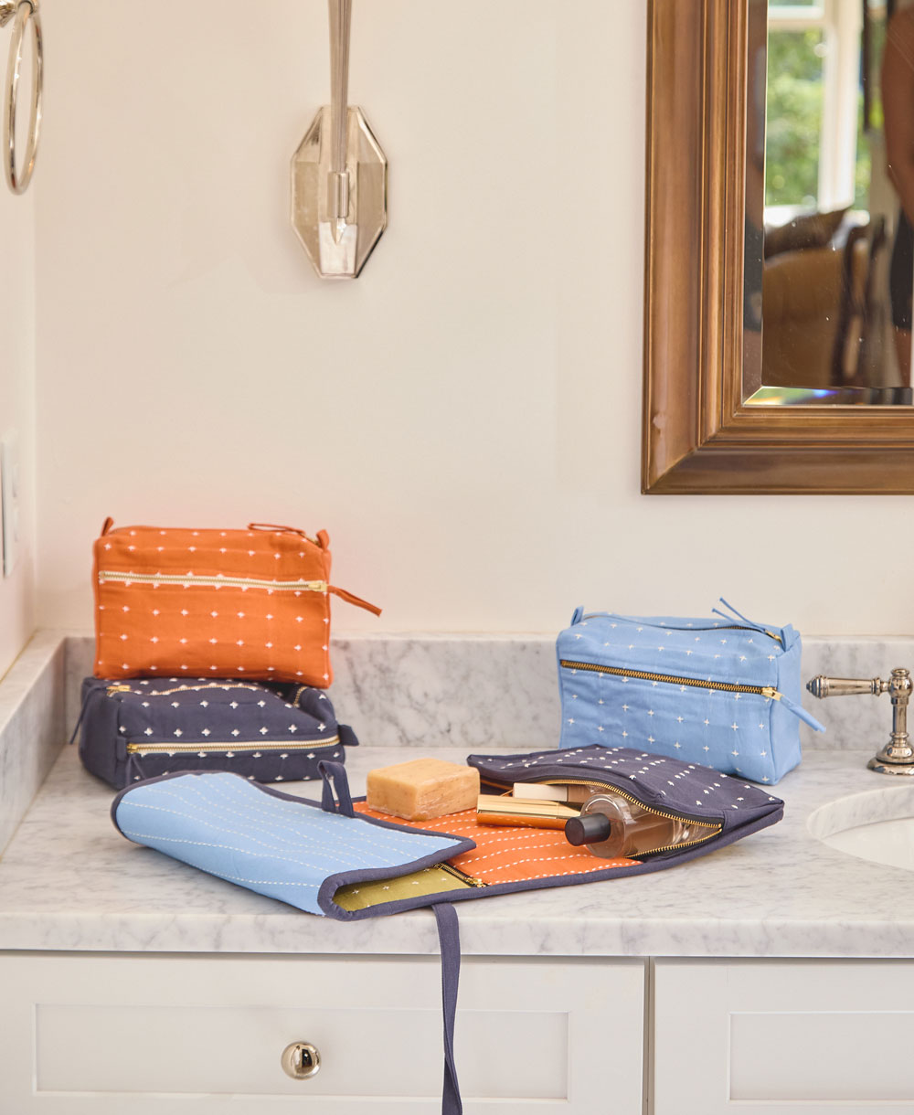 folded travel organizer with toiletries stuffed in the compartments sitting on a gray bathroom vanity
