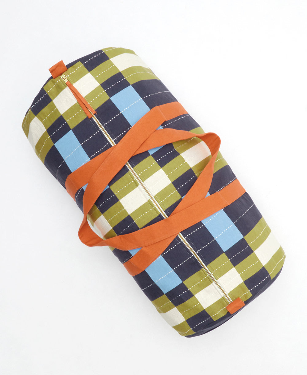 Plaid-patterned weekender duffle bag with orange accents on a white background