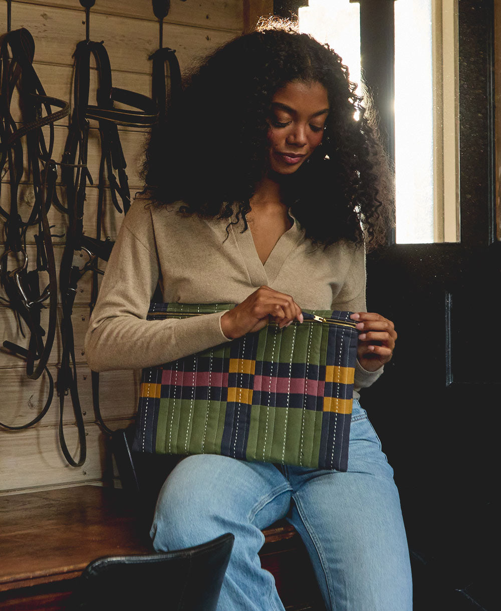 woman holding plaid padded laptop quilted laptop sleeve in tones of hunter green, navy, purple and yellow