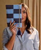 woman holding blue checkered pouch in front of her face