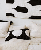 Black and white quilt with abstract patterns on a bed with matching pillows