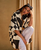 woman sitting on a stool wearing a black and white quilted cocoon jacket