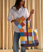 woman holding a colorful canvas tote bag putting a laptop case inside