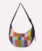 multi-colored checkered crescent bag with a navy blue crossbody strap