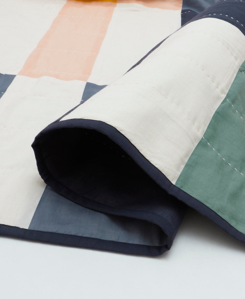 Close-up of a quilt with geometric pattern on a white background
