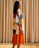 woman standing wearing an orange skirt and quilted colorful cocoon jacket
