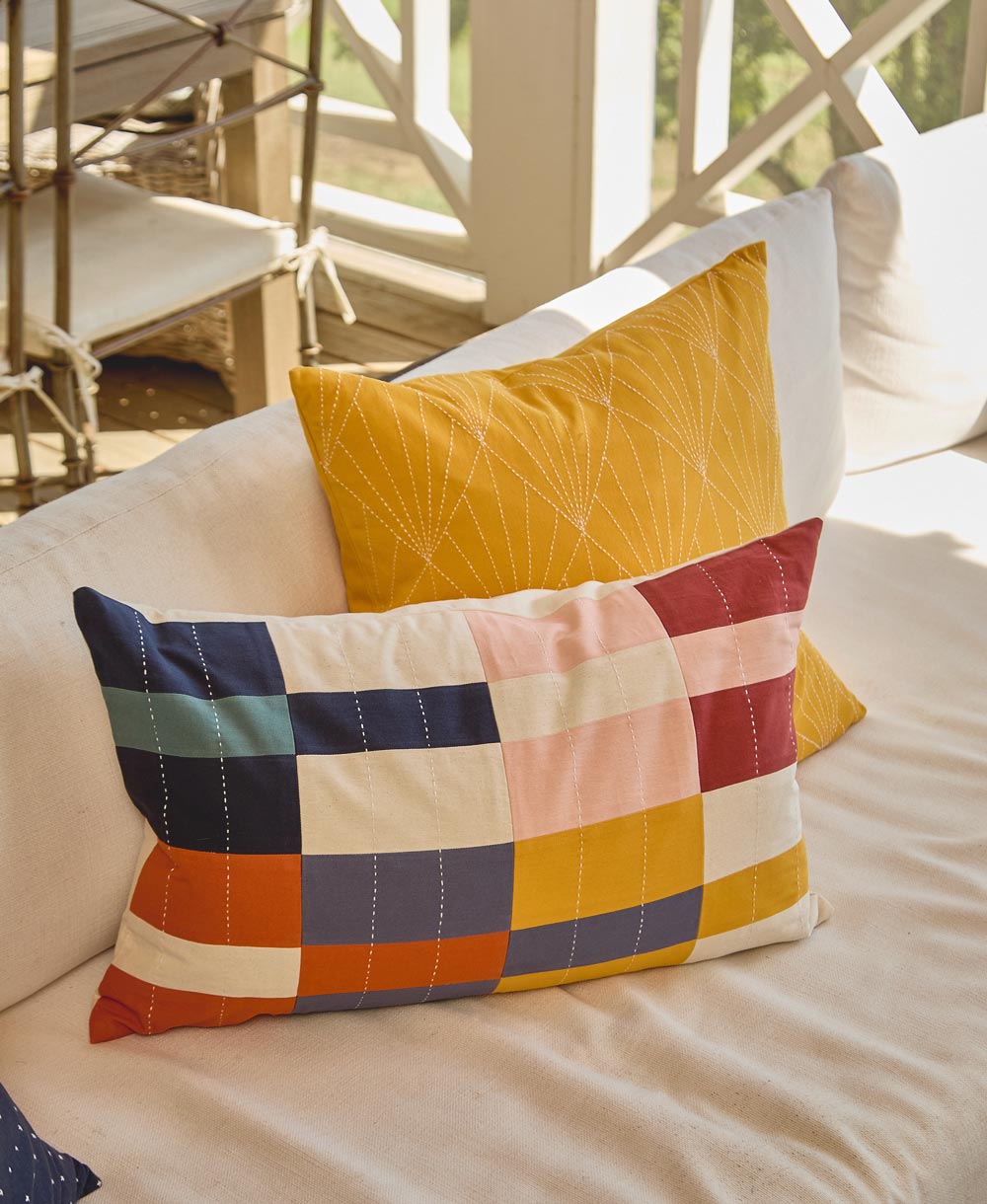 Colorful patchwork pillow on a beige sofa with outdoor furniture in the background