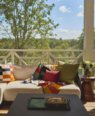 outdoor porch with beige sofa and multi-check patchwork quilt draped over the back