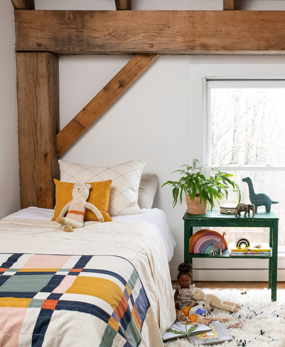 multi plaid baby quilt in bold geometric plaid draped over all white twin kid's bed