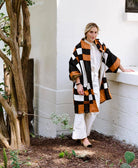 woman wearing patchwork quilted jacket in black, white and camel plaid pattern with all white outfit