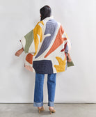 woman wearing quilted floral jacket in white with colorful petal-shaped applique details in cocoon silhouette