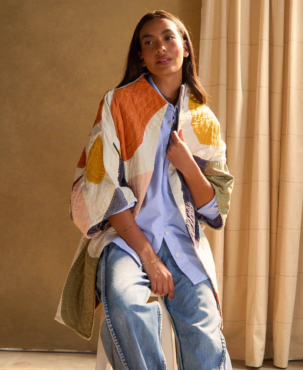 Woman wearing a colorful petal quilted cocoon jacket sitting on a stool