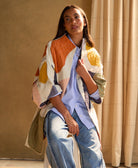 Woman wearing a colorful petal quilted cocoon jacket sitting on a stool