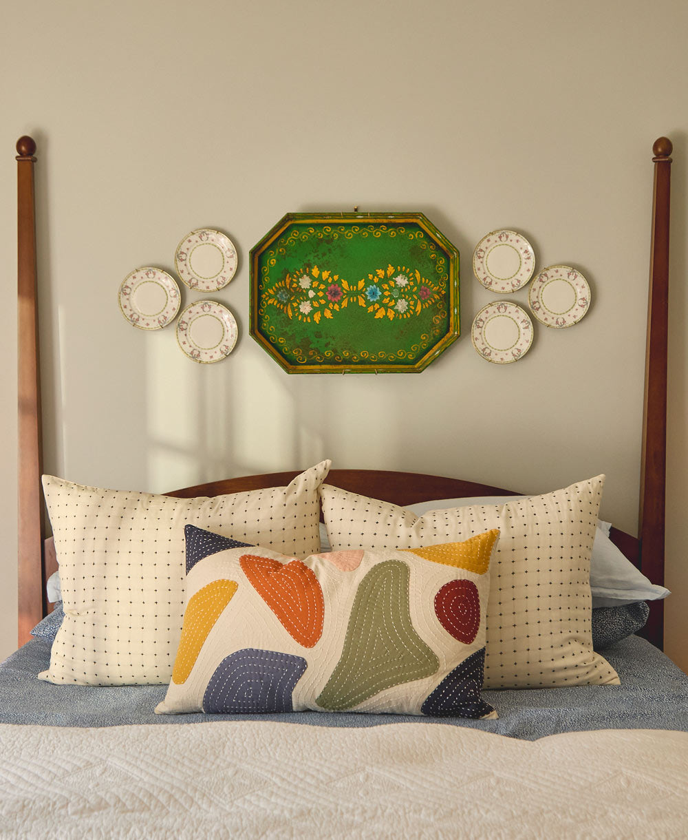 Decorative pillows on a bed with wall art in the background