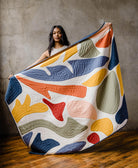 woman holding up modern applique quilt with colorful organic shapes in playful designs