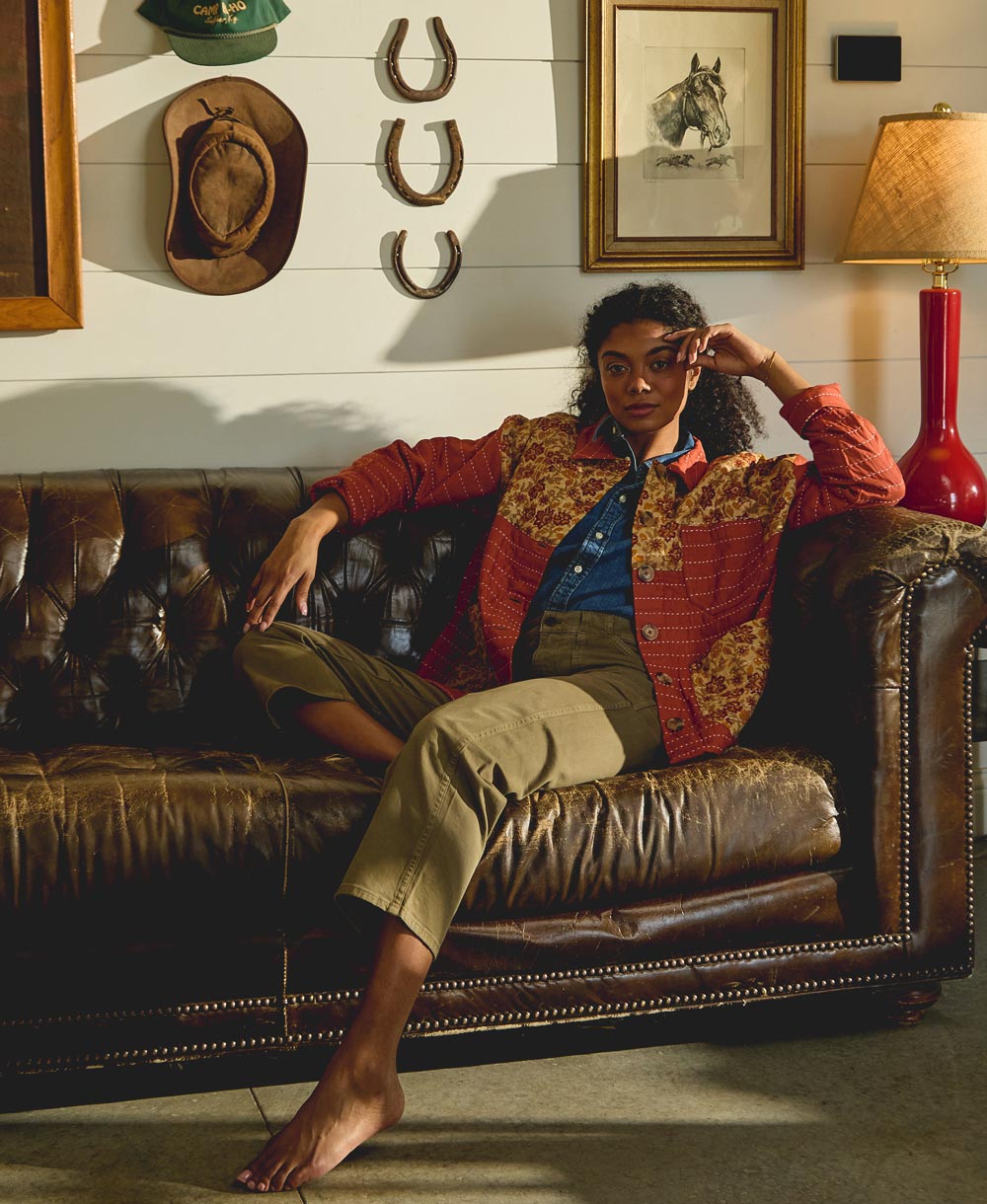 Woman sitting on a brown leather couch in a room with rustic decor