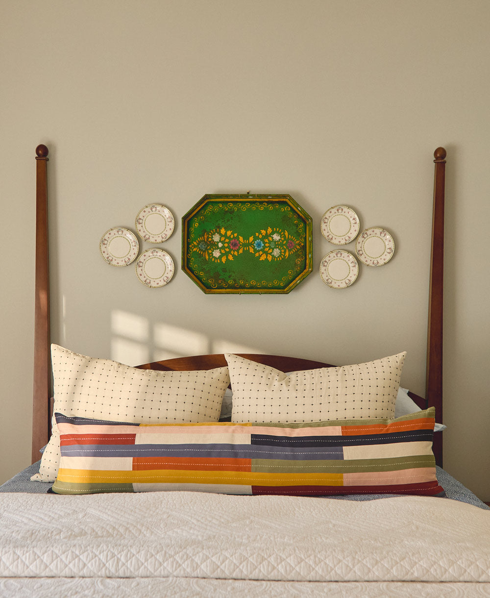 Bedroom with wooden headboard, decorative pillows, and wall art on a beige wall