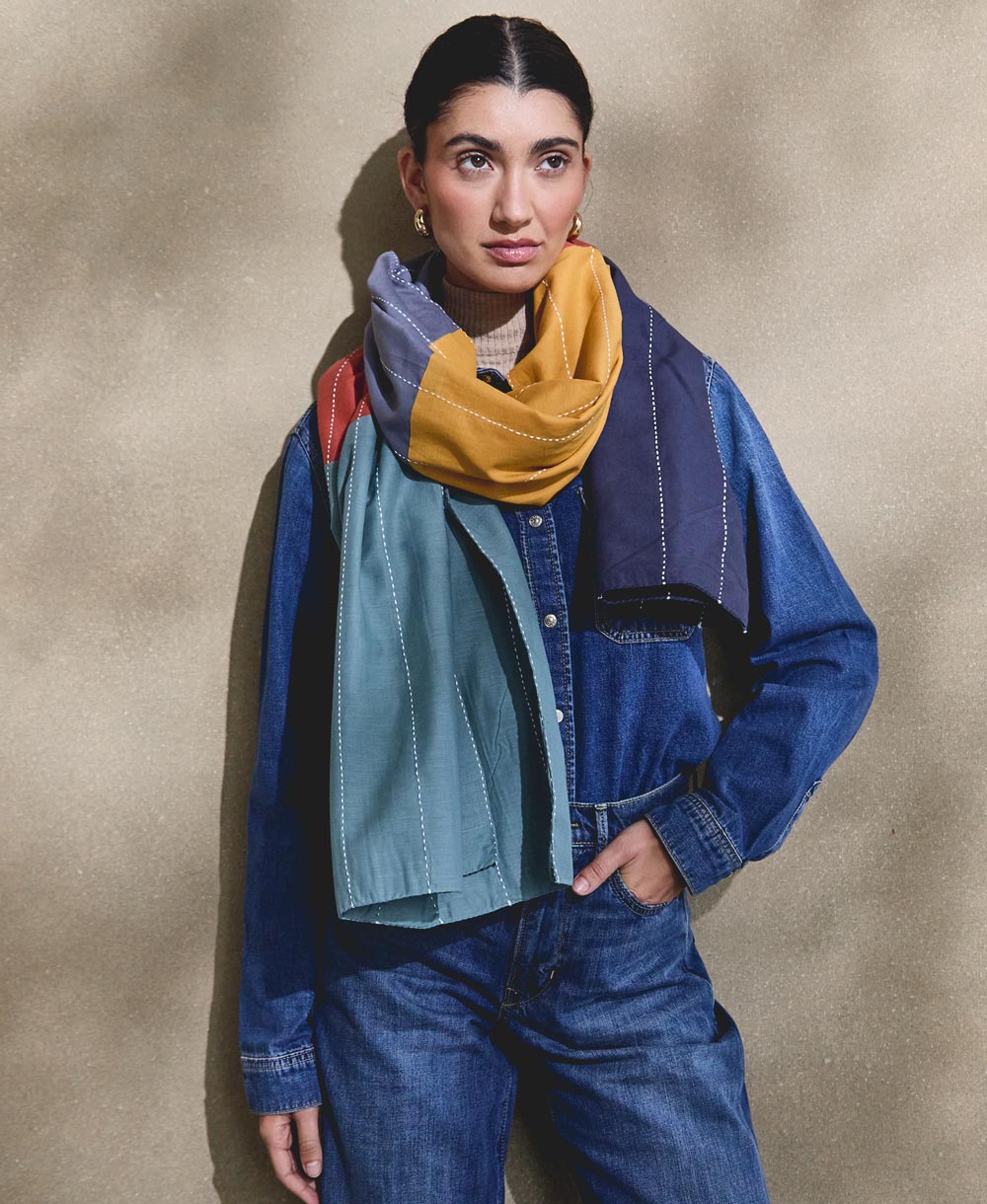 woman wearing all denim outfit with colorful cotton long scarf draped around her neck with white embroidery