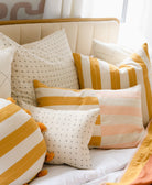 yellow and pink striped throw pillows on modern white bed