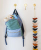 backpack hanging on gold wall hook with children's book and stuffed animal inside