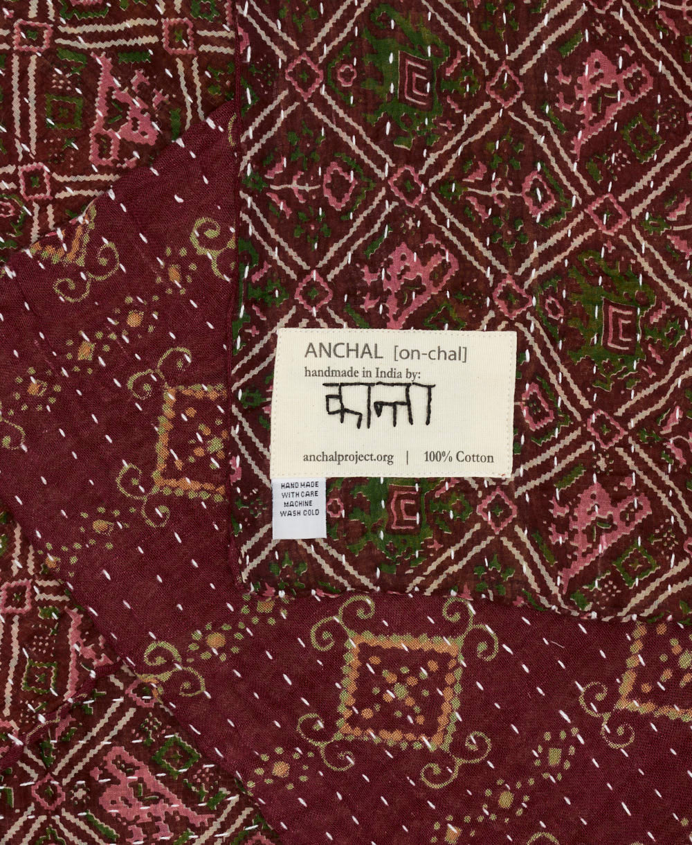 small kantha blanket in deep burgundy purple diamond print with signature of the maker on the tag