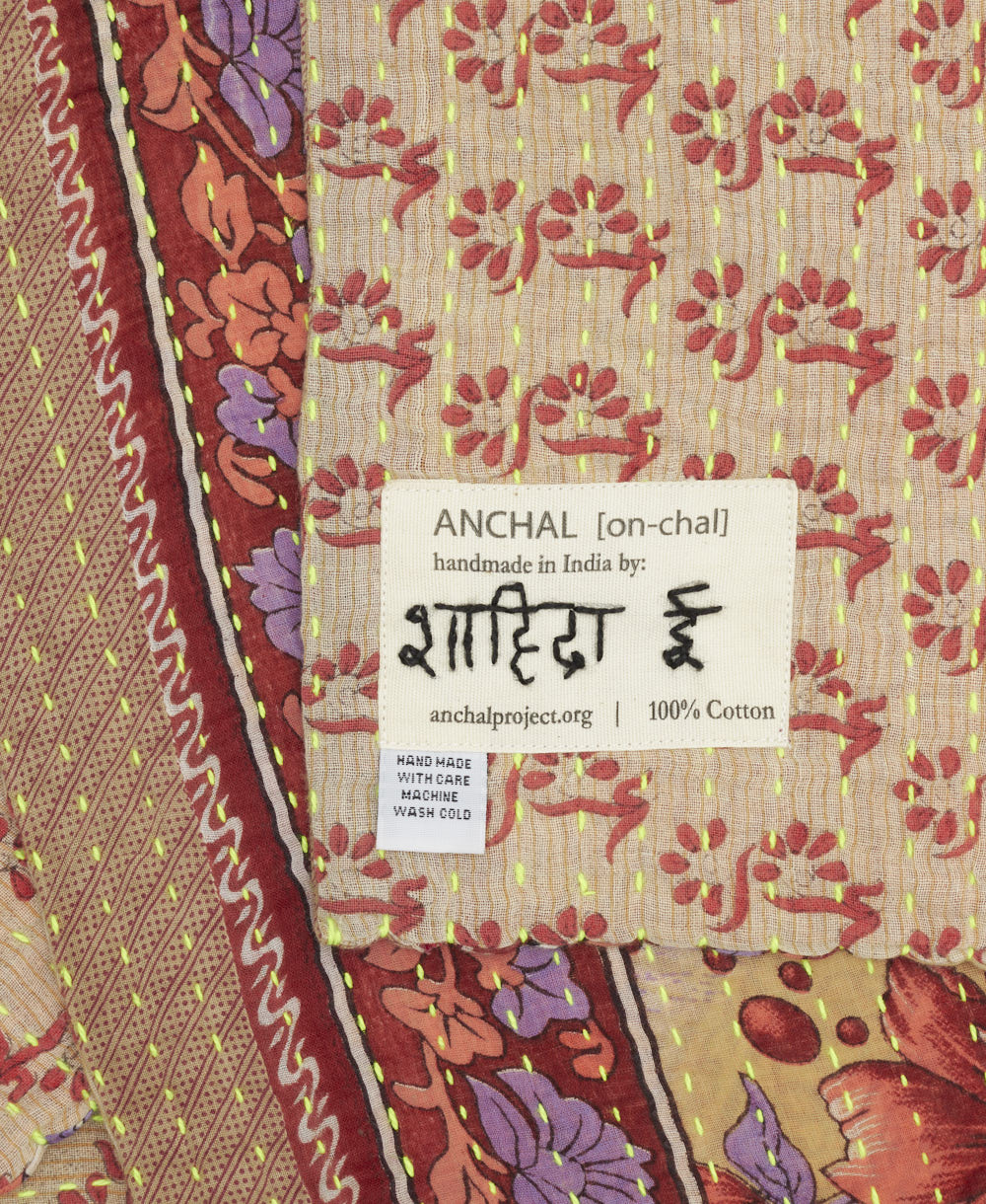 small kantha blanket with signature of the artisan maker on the tag