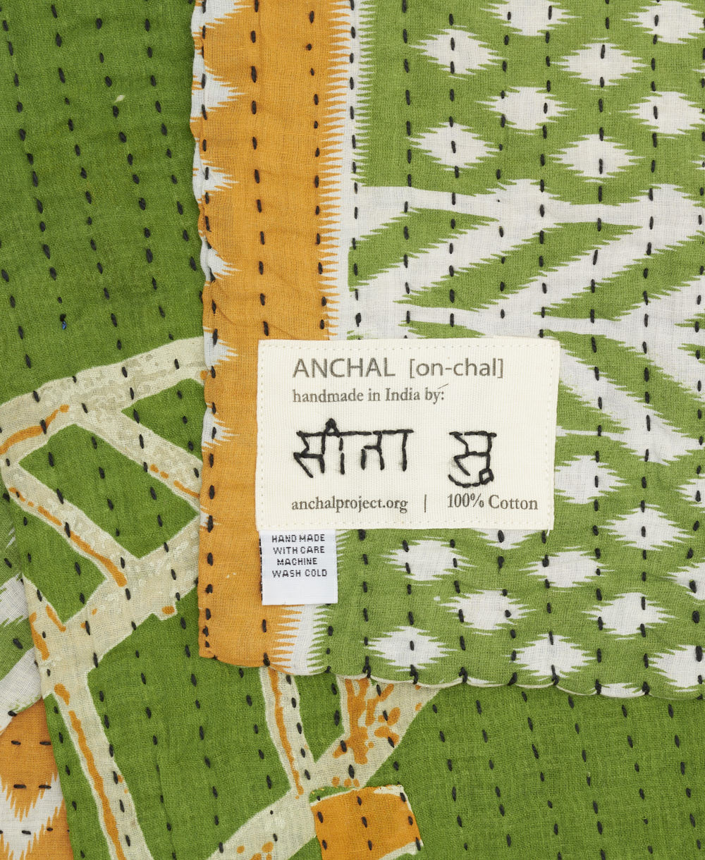 small kantha blanket with signature of the artisan maker on the tag