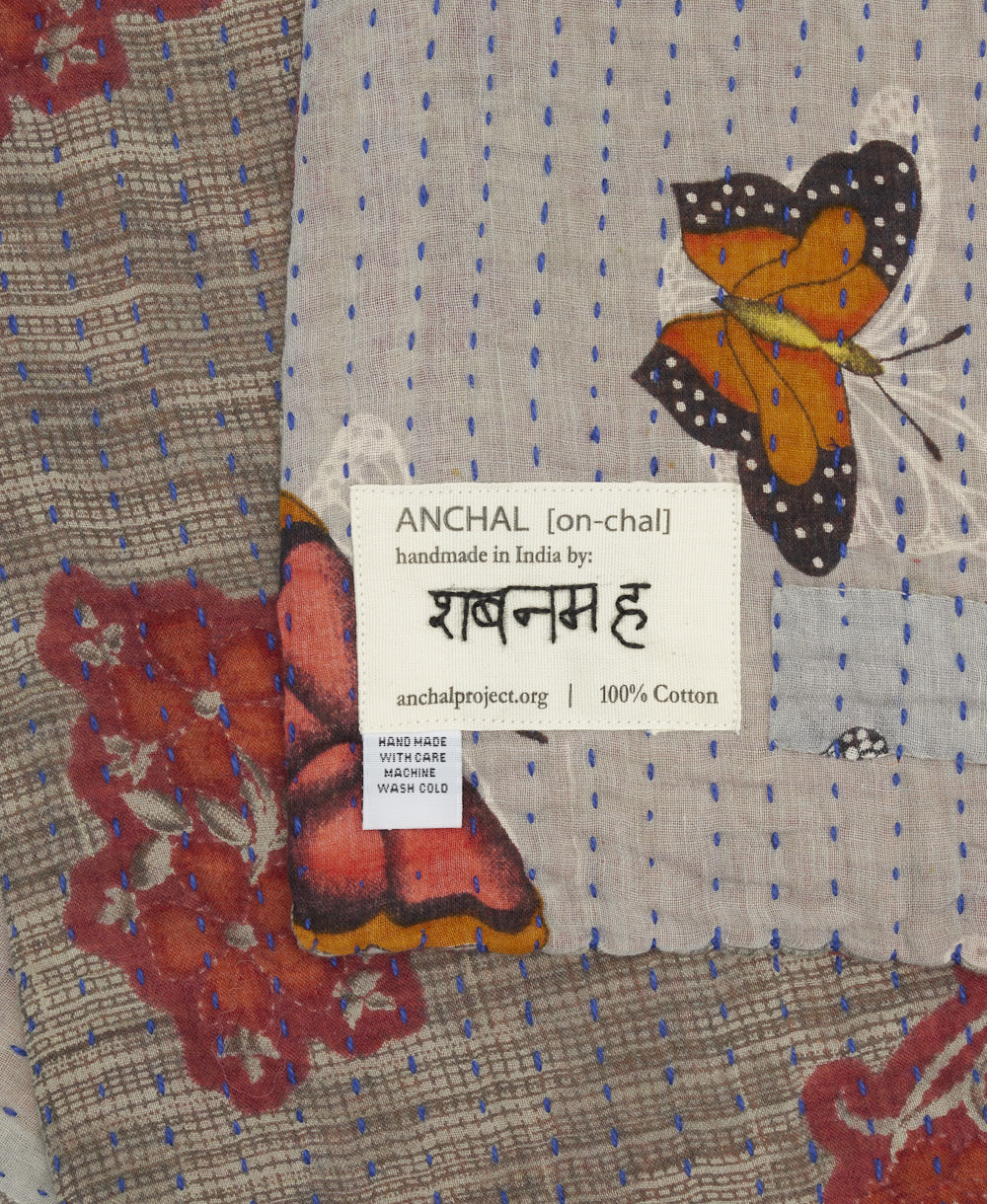 small kantha blanket with signature of the artisan maker on the tag